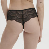 Model wearing Simone Pérèle Karma Shorty Brief in Black from The Foundation, mid-rise fit with scalloped lace and cheeky back design. back view