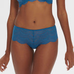 Model wearing Simone Perele Karma Shorty Brief in Bleu Myosotis, mid-rise cut with all-over sheer lace and romantic scalloped trim.