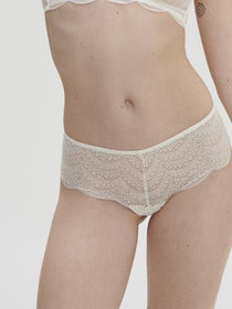 Model wearing Simone Pérèle Karma Shorty Brief in Natural from The Foundation, mid-rise lace design with cheeky back and scalloped edge detail. front view