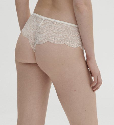 Model wearing Simone Pérèle Karma Shorty Brief in Natural from The Foundation, mid-rise lace design with cheeky back and scalloped edge detail. back view