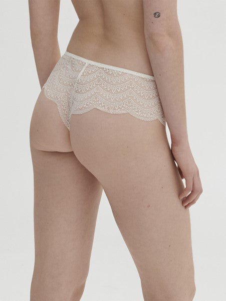 Model wearing Simone Pérèle Karma Shorty Brief in Natural from The Foundation, mid-rise lace design with cheeky back and scalloped edge detail. back view