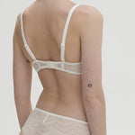 Model wearing Simone Pérèle Karma Wireless Triangle Bra in Natural from The Foundation, with scalloped jacquard lace and convertible back straps. back view