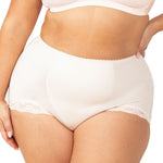 Plus-size model wearing the Something Else Tum-E-Lace Full Brief in Fresh Powder by Triumph, showing high-waisted tummy control fit.
