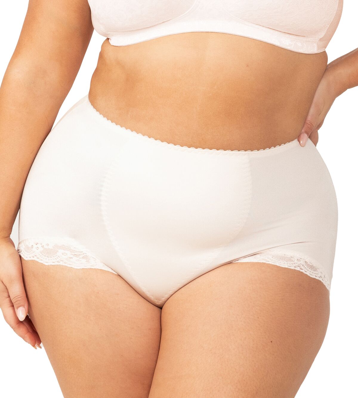 Plus-size model wearing the Something Else Tum-E-Lace Full Brief in Fresh Powder by Triumph, showing high-waisted tummy control fit.