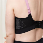 Side-back angle of model wearing Triaction Control Lite Black sports bra, featuring adjustable multi-wear straps