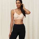 Model in activewear wearing the Triaction Wellness wire-free bra Neutral Beige, perfect for low-impact sports.