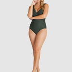 Model in full-length Baku Rococco E–F One Piece Swimsuit, olive green with convertible straps and flattering structure, from The Foundation.