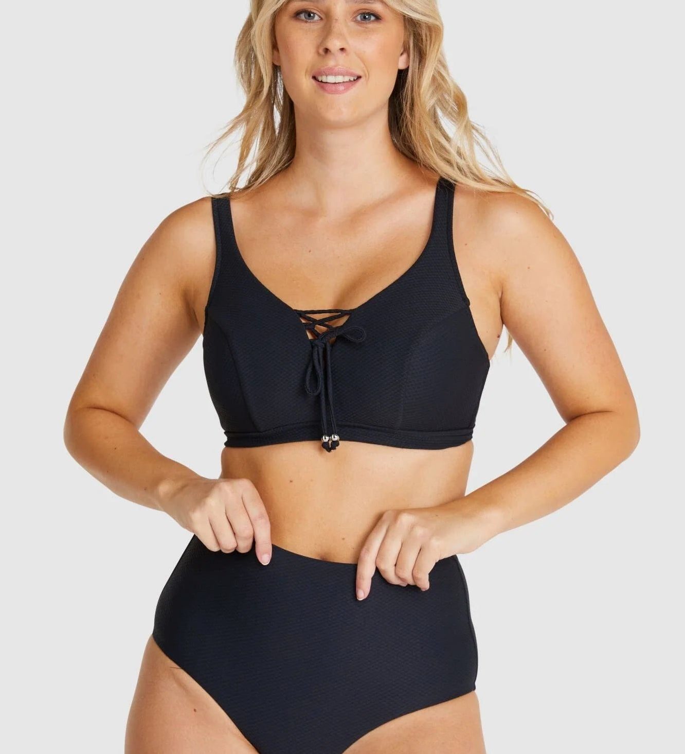Front-facing image of model adjusting Baku Rococco EFG Cup Bra Nero, showing lace-up details and underwire support.