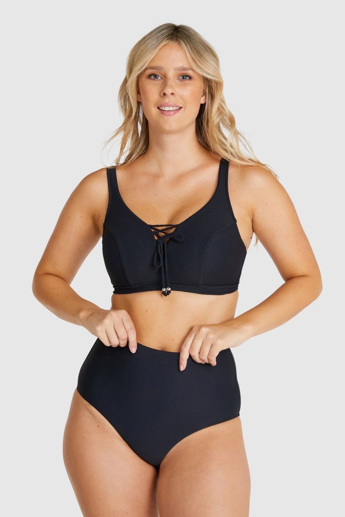 Front-facing image of model adjusting Baku Rococco EFG Cup Bra Nero, showing lace-up details and underwire support.