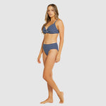 Side view of Model walking in Baku Castaway Navy bikini showcasing high-waisted bottom and bralette top.