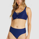 Model wearing Baku Rococco F/G Lace Up Bra Bikini Top in Admiral with high-waisted bottoms in matching navy print.