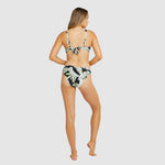 Back view of Model posing in tropical-print regular bikini pant and halter top set with minimal rear coverage.