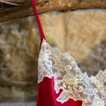 Close-up of white lace trim on the neckline of the Kathryn Chemise in red silk.