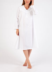 Model wearing Long Sleeve Embroidered White Nightie, featuring a v-neckline with embroidery and ruffled sleeves in soft cotton voile.