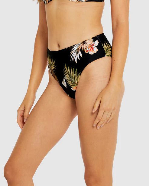 Side view of Baku black mid pant swim brief with full bottom coverage and tropical motif.