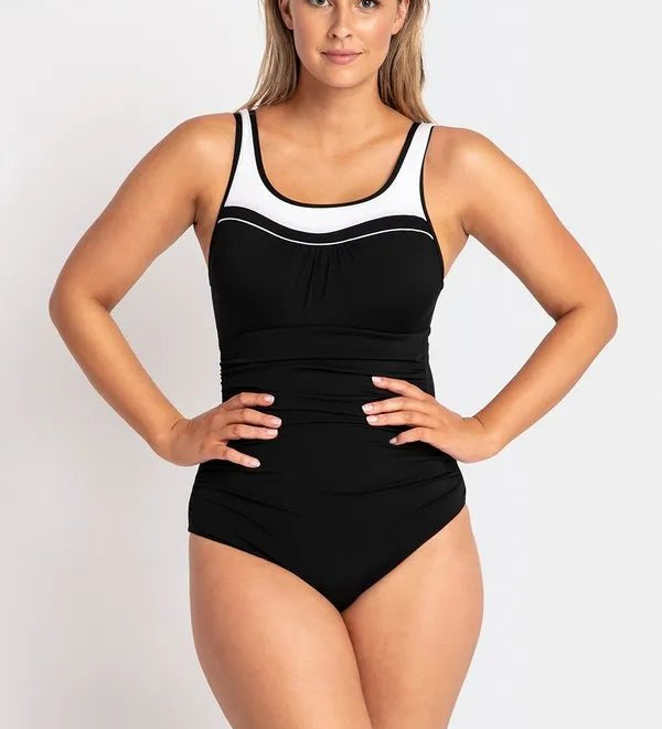 Woman modeling the black POOLPROOF mastectomy scoop one-piece swimsuit with white piping and side gathers.