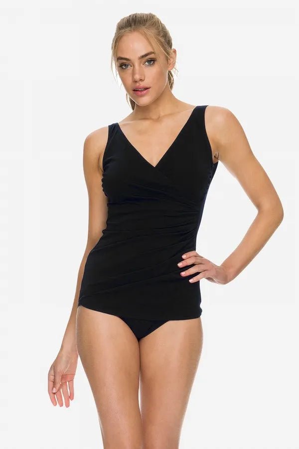 Model wearing the POOLPROOF Sheath black one-piece swimsuit with crossover neckline and wide straps.