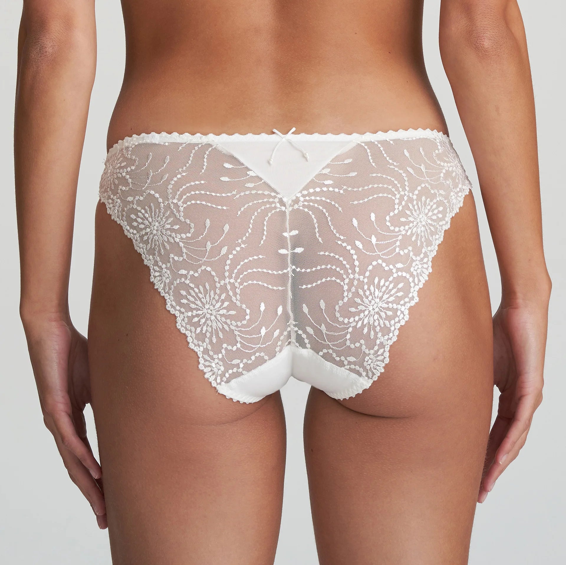 Model wearing Marie Jo Jane Italian Brief in Natural from The Foundation, featuring floral embroidery, sheer lace, and a small pearl-detailed back bow. back view