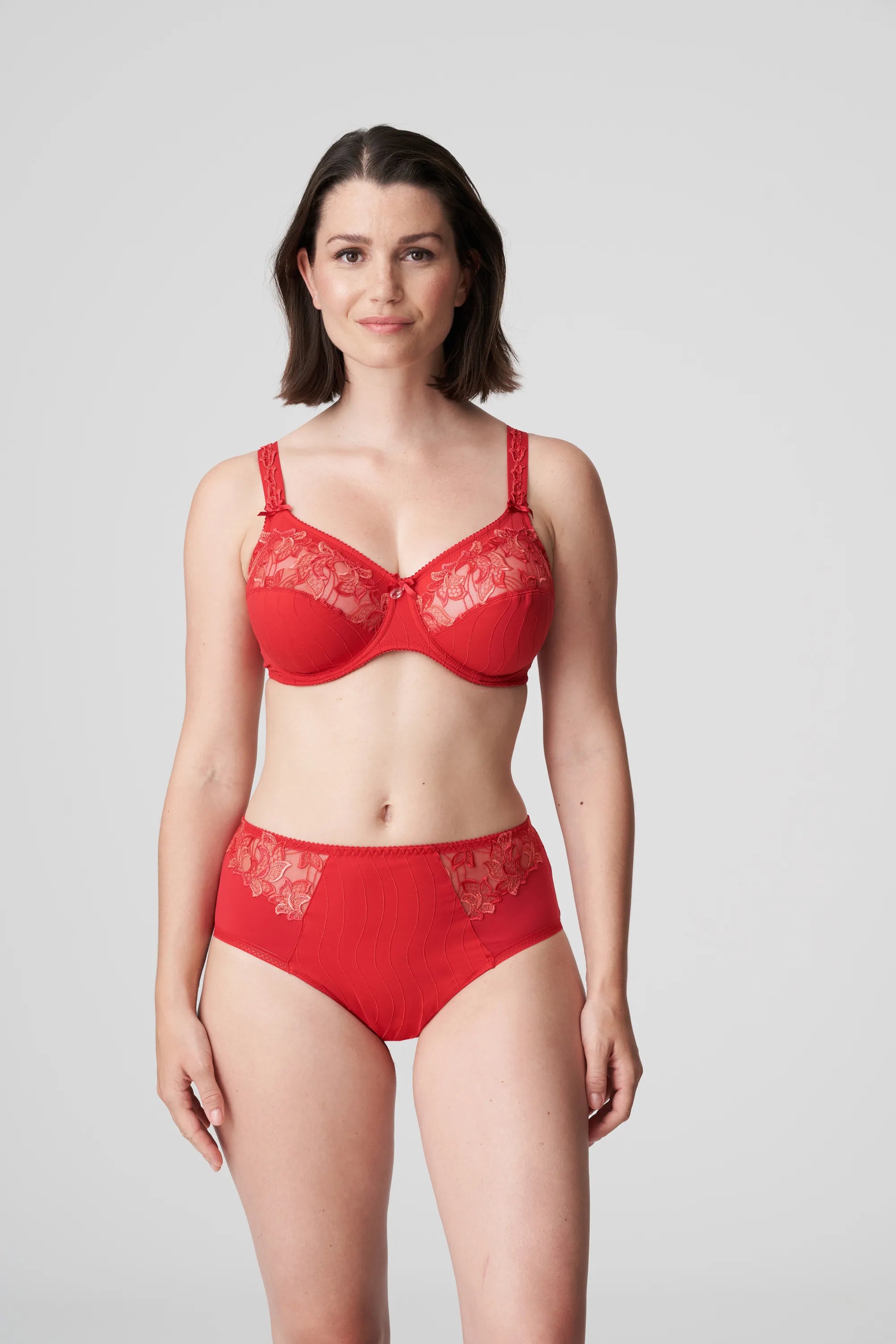 Model wearing PrimaDonna Deauville Full Brief in Scarlet from The Foundation, featuring high waist fit, smoothing support, and lace detail at the hips. front view