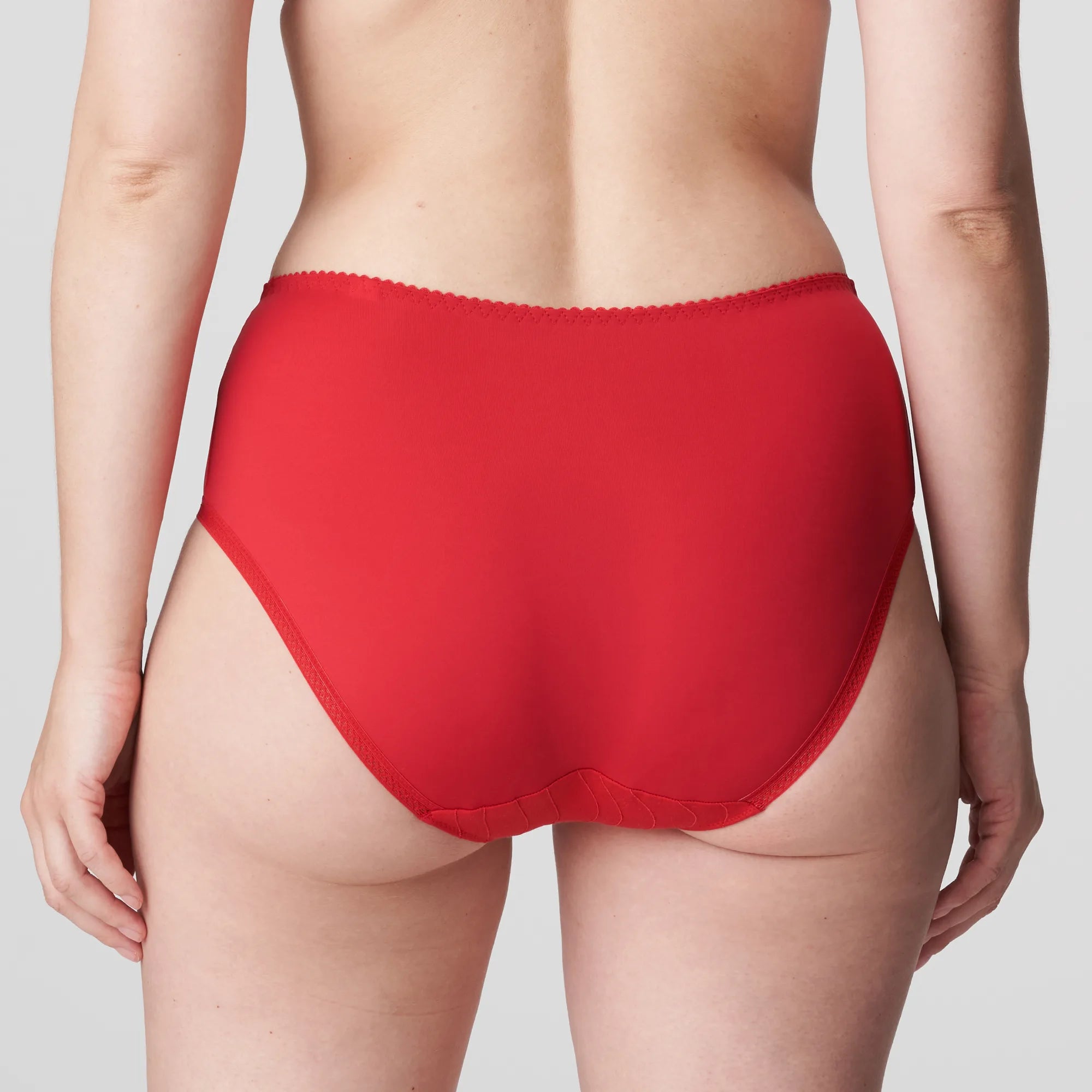 Model wearing PrimaDonna Deauville Full Brief in Scarlet from The Foundation, featuring high waist fit, smoothing support, and lace detail at the hips. back view